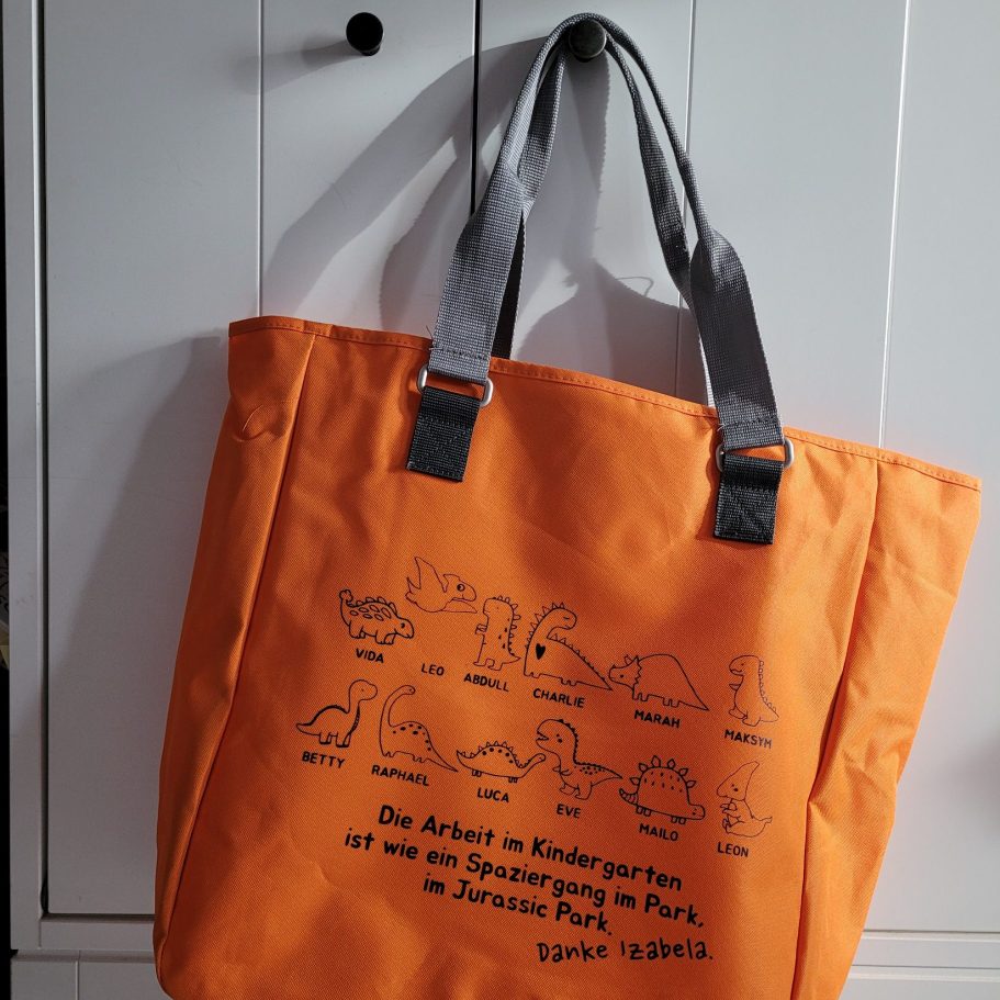 Geplottete Tasche Orange Tasche mit schwarzem Druck von Tieren und einem Text auf Englisch.